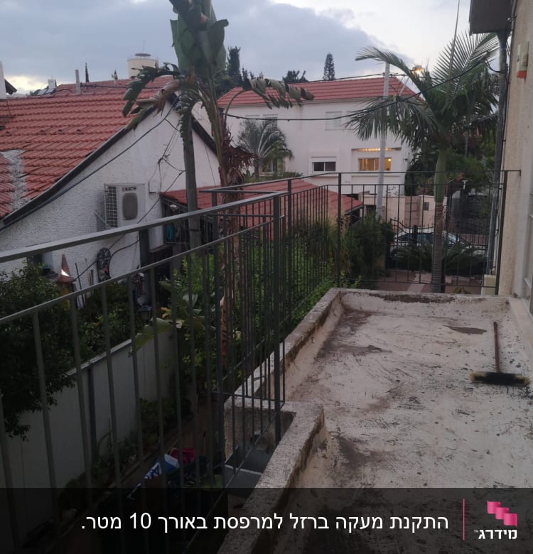 מרפסת עם מעקה מתכת, מטאטא על הרצפה